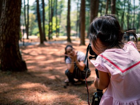 Téléchargez les photos : Un petit appareil photo asiatique prend une photo pour sa mère dans une forêt de pins à Chiang Mai, en Thaïlande. Concept de voyage de détente - en image libre de droit