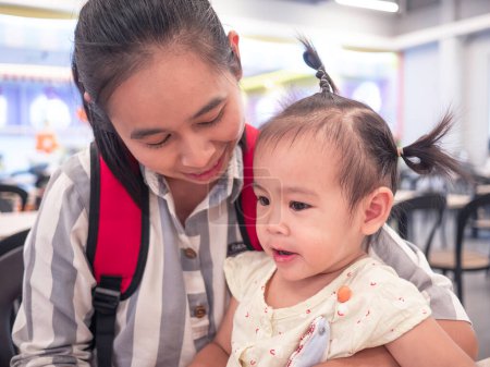 Téléchargez les photos : Asiatique maman regarder sa fille manger des bonbons à la cour de nourriture dans le centre commercial - en image libre de droit