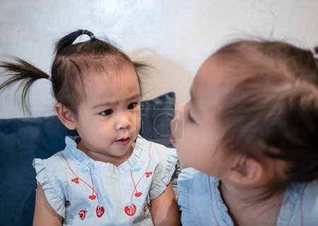 Téléchargez les photos : Asiatique petite fille enfant avec soeur manger collation délicieusement ensemble dans la chambre à coucher - en image libre de droit