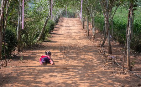 Foto de Niña asiática corriendo en el jardín y cayendo al suelo. Jugar es aprender de los niños - Imagen libre de derechos