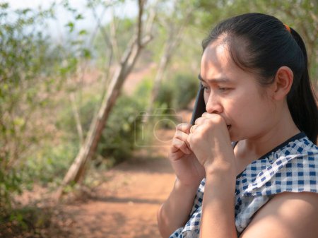 Téléchargez les photos : Asiatiques jeunes femmes parlant par téléphone dans le jardin et toussant avec irritation dans la gorge - en image libre de droit