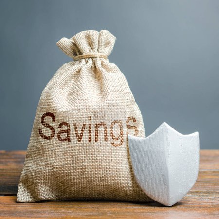 Photo for Bag with the words Savings and protection shield. Concept of protection of savings and cash, guaranteed deposits. Compensation for losses in inflation, safeguarded investment capital - Royalty Free Image