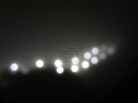Téléchargez les photos : Des lumières abstraites dans le brouillard. Rayons de lumière blanche brillante provenant d'un lampadaire dans le brouillard. noir et blanc - en image libre de droit
