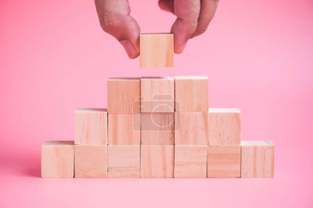 Photo for Man hand building stack of wood cube building blocks - Royalty Free Image