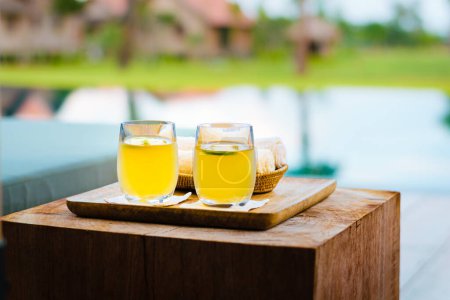 Téléchargez les photos : Deux jaune verres de limonade sur un plateau en bois et un bloc de bois ensuite - en image libre de droit
