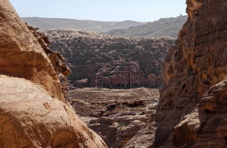 "Blick zwischen Felsen aus der Ferne auf das Zentrum der Nekropole von Petra, Jordanien"