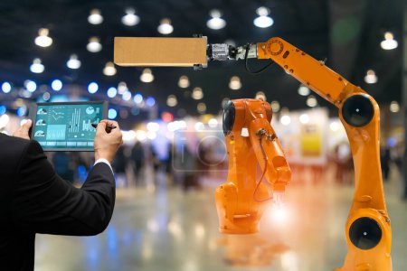 Téléchargez les photos : Robot de commande d'écran tactile d'ingénieur la production de robots d'industrie de fabrication de moteurs de pièces d'usine et bras mécanique - en image libre de droit