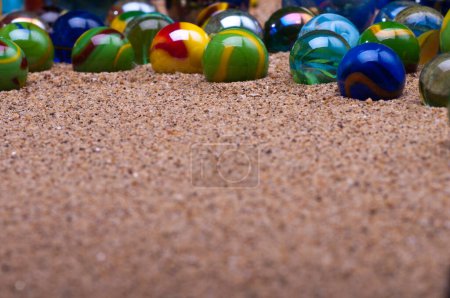 Foto de Bolas de mármol de colores en la arena - Imagen libre de derechos