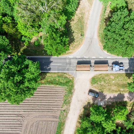 Photo for Aerial photo of a crossing in Germany near Celle over which a tractor with two loaded trailers drives - Royalty Free Image