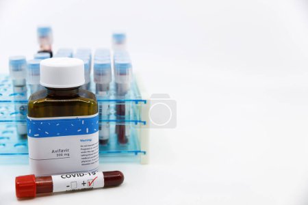 Foto de "Dubai-Emiratos Árabes Unidos-Circa 2020: prueba positiva del Coronavirus frente a la medicina.Concepto de medicina de Avifavir con los tubos de las pruebas de sangre en el fondo.Curación para el coronavirus, tratamiento COVID-19
." - Imagen libre de derechos