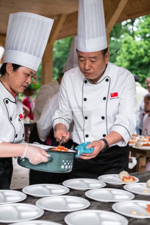 Téléchargez les photos : Cuisinier chinois organise la nourriture sur des assiettes - en image libre de droit