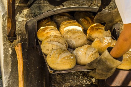 Foto de Pan recién horneado en una bandeja para hornear en un horno con leña - Imagen libre de derechos