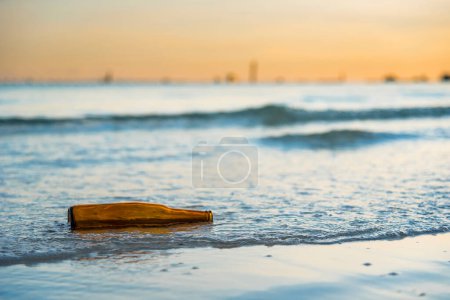 Foto de Botella de vidrio marrón en la playa de Tawaen en el amanecer, el sol estaba saliendo - Imagen libre de derechos