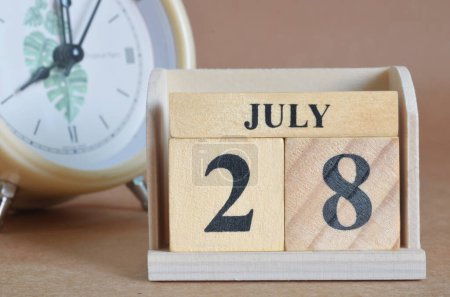 Foto de Calendario de madera con mes de julio y reloj blanco - Imagen libre de derechos