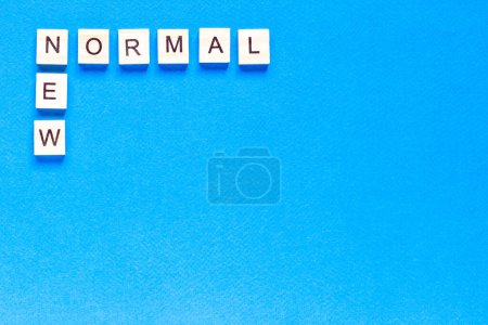 Téléchargez les photos : NEW NORMAL word on wooden alphabet cube. New normal concept. top view, flat layout - en image libre de droit
