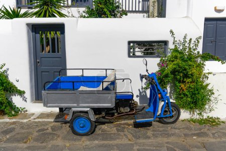 Foto de "Triciclo de motor con cesta aparcada contra casa encalada." - Imagen libre de derechos