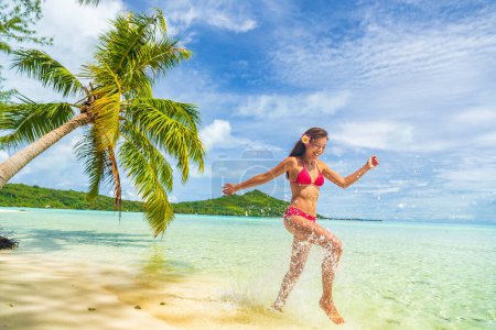 Téléchargez les photos : Voyage vacances plage femme avoir du plaisir, éclaboussures dans l'eau au paradis - en image libre de droit