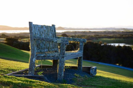 Téléchargez les photos : Un vieux banc recouvert de mousse et de toile d'araignée, surplombant un beau parcours de golf vert - en image libre de droit
