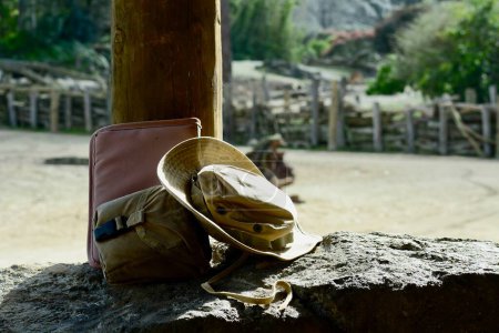 Foto de Una foto de cerca de un viejo sombrero de vaquero envejecido y una bolsa de viaje, dejada en piedra en el desierto. - Imagen libre de derechos
