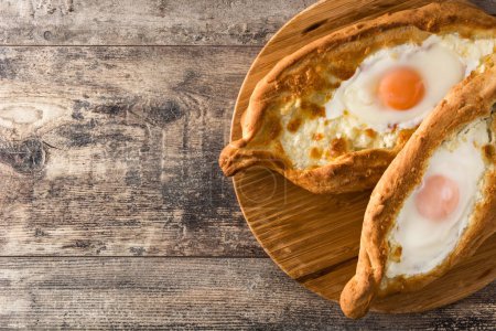 Photo for Traditional Adjarian Georgian khachapuri with cheese and egg on wooden table - Royalty Free Image