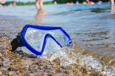 Photo for Scuba diving mask lost and thrown ashore with people resting in the background - Royalty Free Image