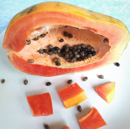 Photo for "Orange color fresh papaya kept in white background with cut pieces and rich in fibre Vitamin C and antioxidants Boosts your immunity Good for diabetics and eyes" - Royalty Free Image