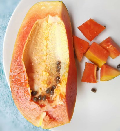 Photo for "Orange color fresh papaya kept in white background with cut pieces and rich in fibre Vitamin C and antioxidants Boosts your immunity Good for diabetics and eyes" - Royalty Free Image