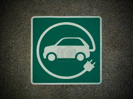 Téléchargez les photos : EV - panneau de borne de recharge de véhicule électrique. Signe "E" sur la texture asphaltée - en image libre de droit