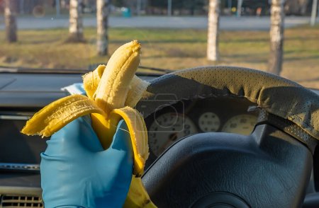 Téléchargez les photos : Nourriture rapide et sûre, banane dans la main du conducteur de voiture - en image libre de droit