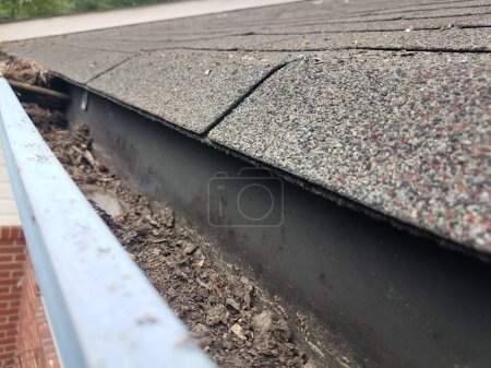 Photo for Dirty metal gutter with roof shingles on house - Royalty Free Image