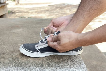 Foto de Los atletas masculinos atan un cordón de zapatos para prepararse para el ejercicio por la carrera. El ejercicio es un ejercicio saludable. - Imagen libre de derechos