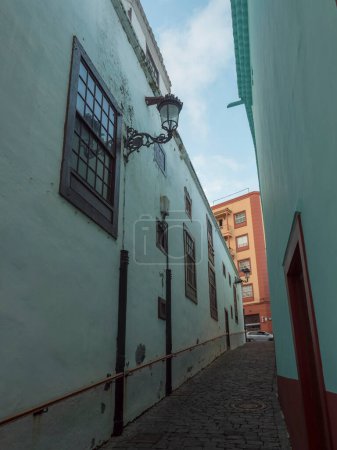 Photo for Empty narrow street at Santa Cruz de la Palma old city center with turquoise green traditional house, lantern and cobble stone paving. La Palma, Canary Islands, Spain - Royalty Free Image