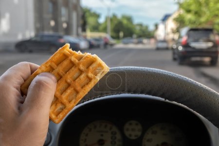 Téléchargez les photos : "nourriture, biscuits dans la main d'un conducteur de voiture tout en conduisant dans la ville" - en image libre de droit