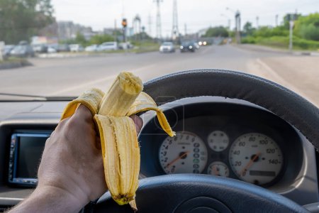 Téléchargez les photos : Nourriture, banane dans la main du conducteur au volant de la voiture - en image libre de droit