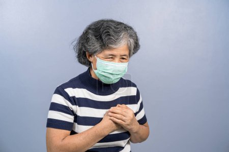 Téléchargez les photos : Asiatique Vieille femme portant un masque chirurgical du visage et ressentant douleur - en image libre de droit