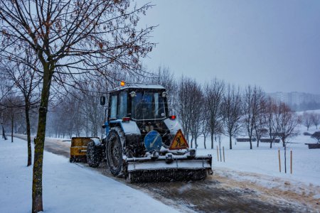 Foto de El tractor limpia la nieve de la acera durante las nevadas - Imagen libre de derechos