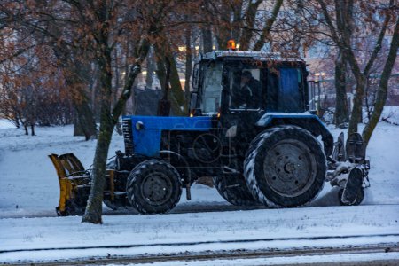 Foto de Tractor Balarus limpia la nieve de la acera durante las nevadas - Imagen libre de derechos