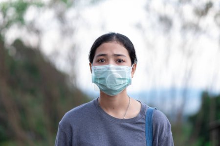 Téléchargez les photos : Jeune femme asiatique portant un masque médical tout en étant debout à l'extérieur - en image libre de droit