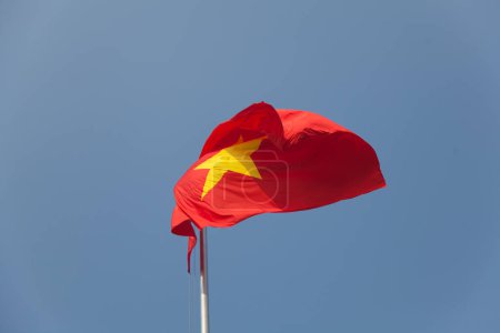 Téléchargez les photos : Drapeau national du Vietnam soufflant dans le vent contre un ciel bleu parfait - en image libre de droit