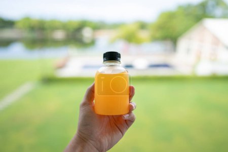 Téléchargez les photos : Jus d'orange sain désintoxication. Gros plan de bouteille d'orange fraîche à la main - en image libre de droit