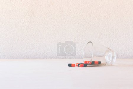 Photo for Pills in glass on wooden floor and concrete background - Royalty Free Image