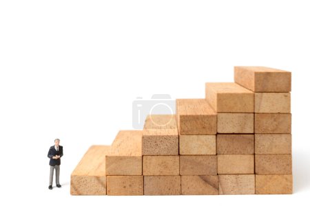 Photo for Miniature people: Businessman standing on wood blocks isolated on white background - Royalty Free Image