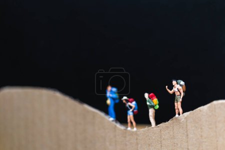 Téléchargez les photos : Personnes miniatures : Voyageur avec sac à dos marchant sur le papier - en image libre de droit