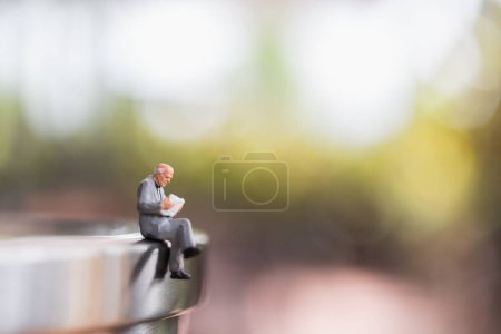 Foto de Personas en miniatura: Empresario sentado leyendo libro al aire libre - Imagen libre de derechos