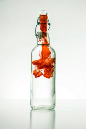Téléchargez les photos : Fumée rouge en bouteille sur fond blanc - en image libre de droit