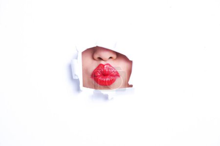 Téléchargez les photos : Vue des lèvres rouges plissées à travers un trou de papier - en image libre de droit