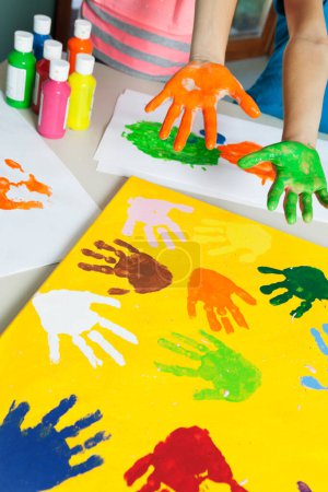 Photo for Close-up of paint covered hands and colorful handprints on papers - Royalty Free Image