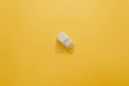 Téléchargez les photos : Un chargeur blanc sur une table jaune - en image libre de droit