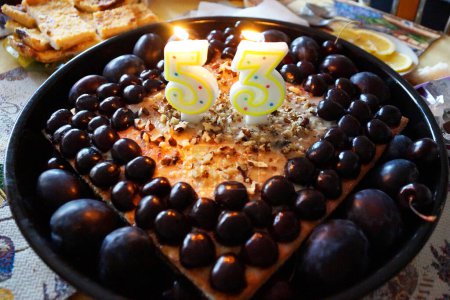 Foto de El número 53 de las velas sobre el pastel de frutas con las cerezas - Imagen libre de derechos
