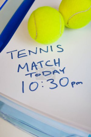 Photo for Tennis balls on note indicating match timing - Royalty Free Image